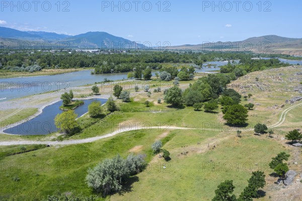 Wide landscape with river, green fields and hills under a blue sky, view from the cave town of Uplistsikhe, Kura or Mtkwari river, Inner Kartli region, Shida Kartli, Georgia