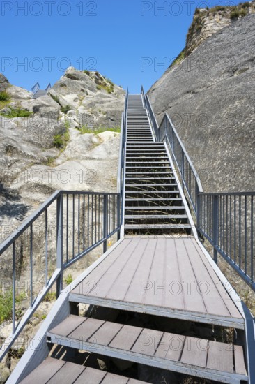 Metal staircase leads up between rocky walls under blue sky, Uplistsikhe cave town, Uplistsikhe, Inner Kartli region, Shida Kartli, Georgia