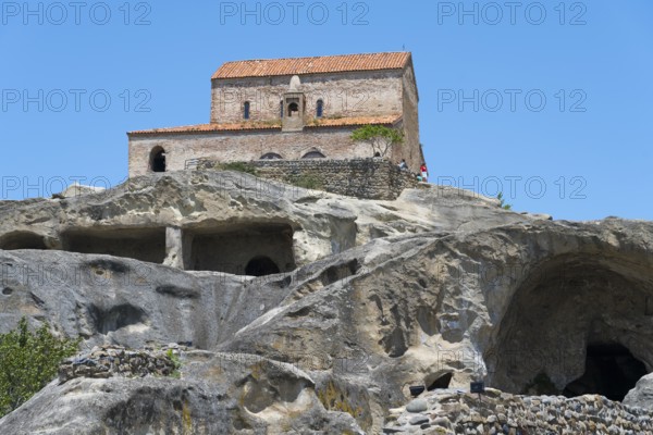 Church on a rock with caves below and ancient architecture against a blue sky, 10th century princely church, Uplistsikhe cave town, Uplistsikhe, Inner Kartli region, Shida Kartli, Georgia