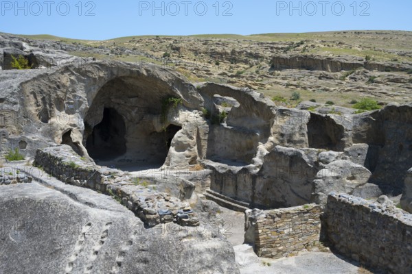 Rock formations with caves and ruins in a vast landscape under blue sky, Uplistsikhe cave town, Uplistsikhe, Inner Kartli region, Shida Kartli, Georgia
