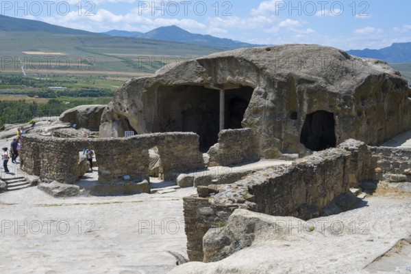 Ancient cave system with ruins in a vast landscape, visitors explore, Tamaris Darbasi, Tamaras Hall, Uplistsikhe cave town, Uplistsikhe, Inner Kartli region, Shida Kartli, Georgia