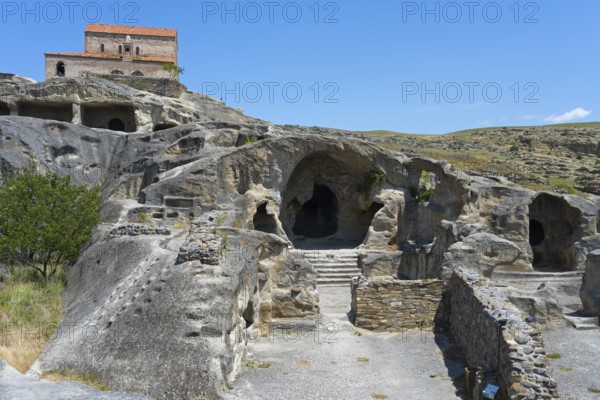 Ancient cave with entrances, dominated by an old building and surrounded by nature, 10th century princely church, Uplistsikhe cave town, Uplistsikhe, Inner Kartli region, Shida Kartli, Georgia