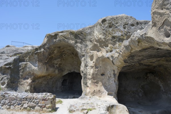 Rock formation with cave entrances under blue sky in natural landscape, Uplistsikhe cave town, Uplistsikhe, Inner Kartli region, Shida Kartli, Georgia