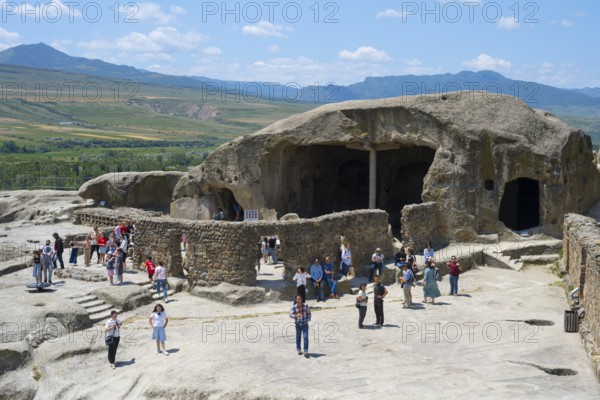 Tourists visit old caves and rock formations on a sunny day, Tamaris Darbasi, Tamara's Hall, Uplistsikhe cave town, Innerkartli region, Shida Kartli, Georgia
