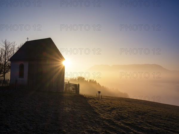 Sunbeams at a chapel above high fog at sunrise, Untersberg in the background, Högl, Anger, Berchtesgadener Land, Upper Bavaria, Bavaria, Germany