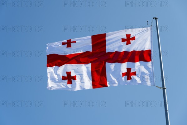 White flag with red crosses flying against a blue sky, flag of Georgia