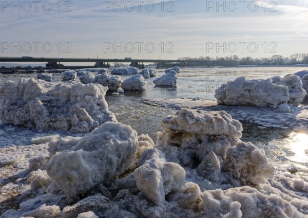 Ice skating on the Elbe with small icebergs on the water and on the banks of the Elbe Island near Geesthacht on a cold winter day. Geesthacht, Schleswig-Holstein, Germany. In the background, the Elbe bridge of the B 404