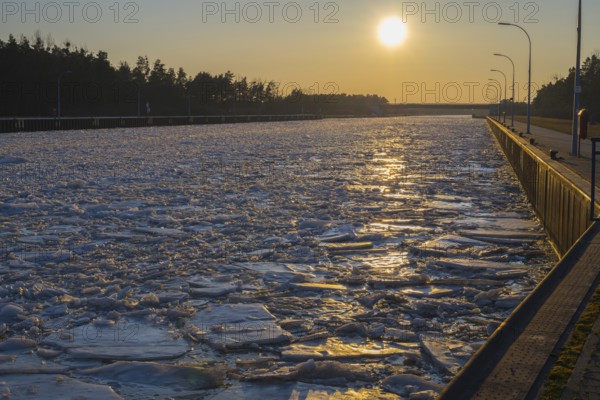 Frozen channel at sunset with reflecting light and wooded banks, ice floes, Elbe-Havel Canal, Jerichower Land, Saxony-Anhalt, Germany