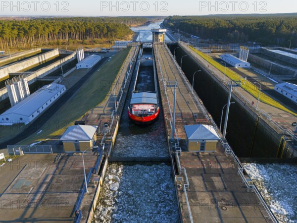 A ship in a lock surrounded by buildings, with a snowy forest and icy conditions, aerial view, cargo ship Cologne 2 and Cologne 1, Hohenwarthe lock, Elbe-Havel Canal, Jerichower Land, Saxony-Anhalt, Germany