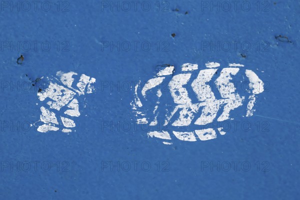 White paint imprint of a shoe sole on a blue painted surface