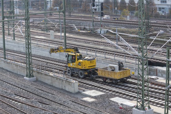 Yellow excavator next to railroad tracks on a large construction site in an urban environment, Untertürkheim parking lot, Stuttgart, Baden-Württemberg, Germany