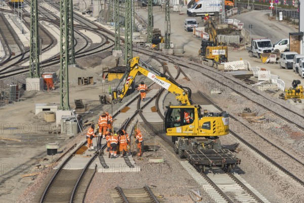 Rail construction with a group of workers and a yellow construction machine vehicle on the construction site, Untertürkheim parking station, Stuttgart, Baden-Württemberg, Germany