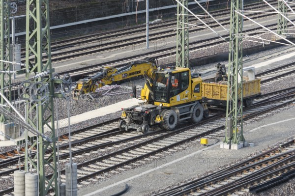 A yellow rail vehicle on a railway line surrounded by construction site equipment, Untertürkheim parking station, Stuttgart, Baden-Württemberg, Germany