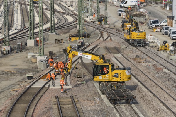 Track construction on a construction site with groups of construction workers and a yellow excavator, Untertürkheim parking station, Stuttgart, Baden-Württemberg, Germany
