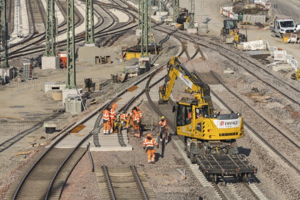 Rail construction workers wearing safety clothing at work next to a large machine, Untertürkheim parking station, Stuttgart, Baden-Württemberg, Germany