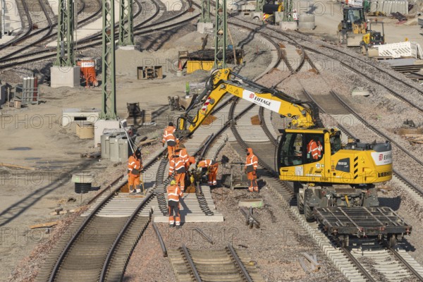 Team of construction workers wearing orange safety equipment working on tracks, Untertürkheim parking station, Stuttgart, Baden-Württemberg, Germany