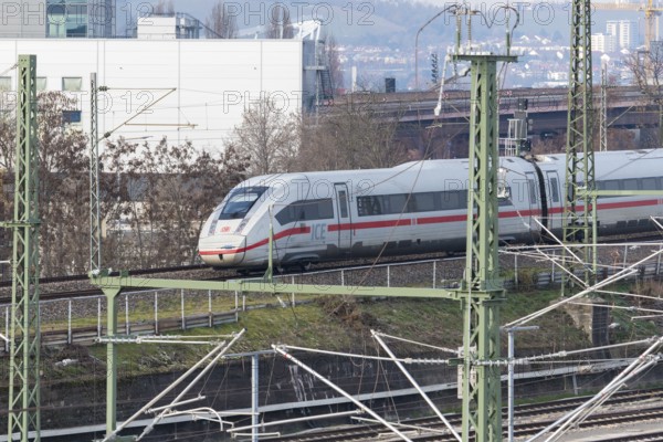 An ICE high-speed train travels on rails through an urban landscape with power poles, Untertürkheim parking station, Stuttgart, Baden-Württemberg, Germany