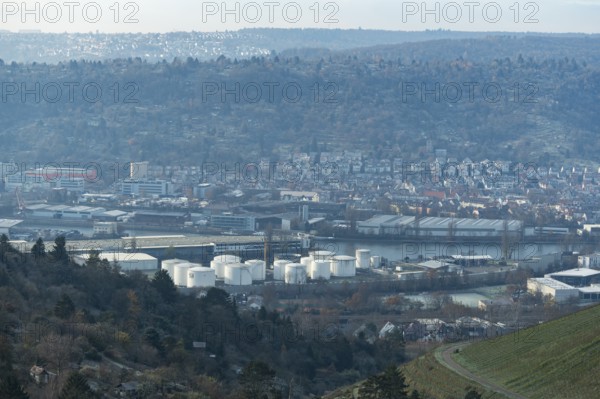 Industrial plant with white tanks in front of a hilly landscape covered with houses, view of harbour, Untertürkheim, Stuttgart, Baden-Württemberg, Germany