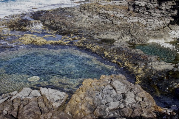 Rocky coast with cave and clear water. Waves and erosion shape the dark rock formations, Yaiza Lanzarote