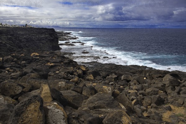 Coast with rough rocks and waves under a cloudy sky. Dark and stormy atmosphere