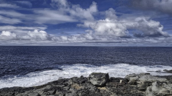 Rough sea under cloudy sky meets rocky coast. Atmospheric and wild with moving waves, Yaiza Lanzarote