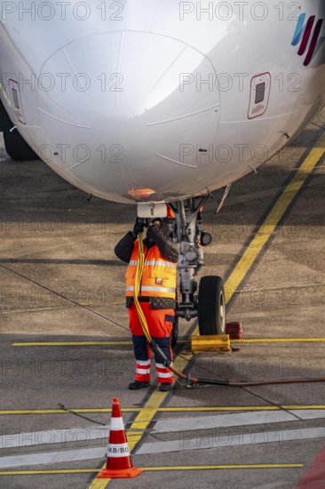 Ground crew installs ground power, power supply for the aircraft after stopping at the parking position, at the terminal, gate, at the Cologne/Bonn airport passenger bridge, CGN, North Rhine-Westphalia, Germany