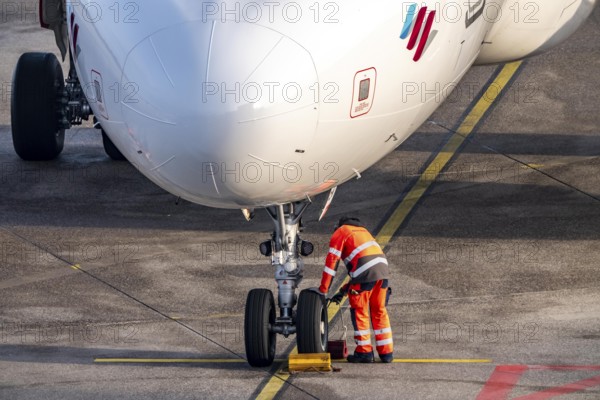 Ground crew positions brake blocks on the chassis, after stopping at the parking position, at the terminal, gate, at the Cologne/Bonn airport passenger bridge, CGN, North Rhine-Westphalia, Germany