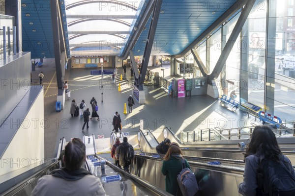 People on escalator of modern architecture of railway station concourse building, Reading, Berkshire, England, UK