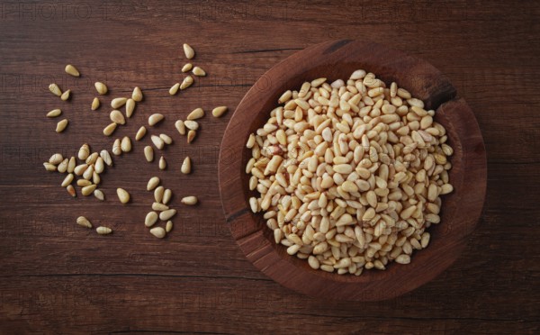 Peeled pine nuts, in a wooden bowl, on a wooden table, close-up, no people