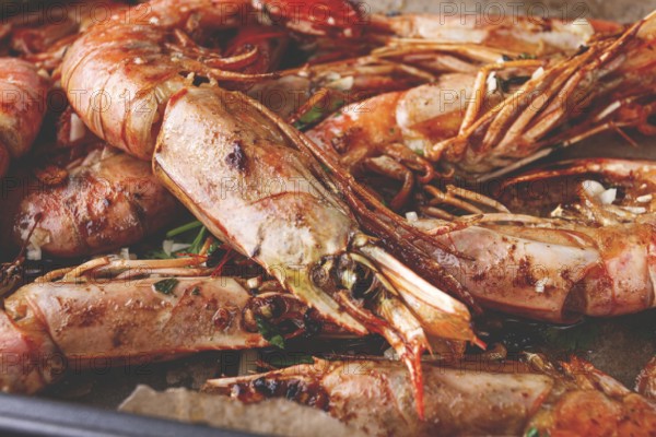 Juicy grilled shrimp, placed on a baking sheet lined with parchment paper, garnished with herbs and lemon
