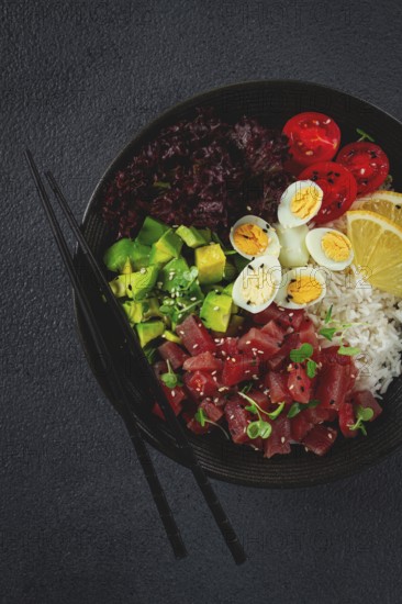 Fresh poke bowl with tuna, avocado, and vegetables served on a black plate