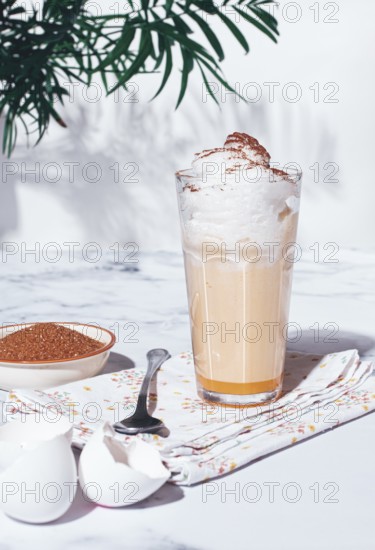Eggnog drink, egg yolk, in a glass, with cream and cinnamon, sunlight