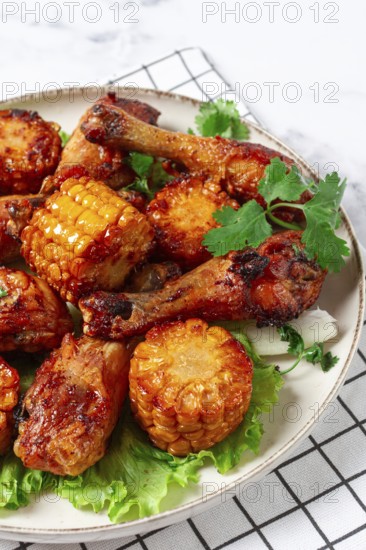 Fried chicken drumsticks, Mexican style, with corn, on a plate, close-up