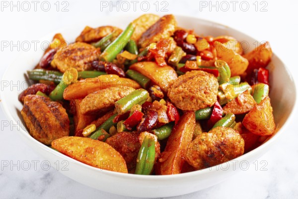 Steakhouse pfanne, fried potato slices, with meatballs, and vegetable mixture, on a white plate