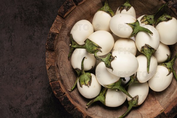 White mini eggplant, in a wooden bowl, on the table, close-up