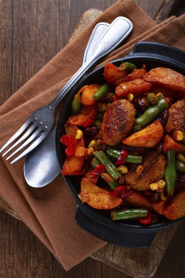 Steakhouse pfanne, fried potato slices, with meatballs, and vegetable mixture, on a black plate