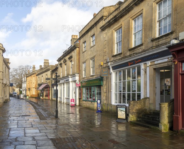 Wet pavements after rain in pedestrianised High Street are of town centre of Corsham Wiltshire, England, UK - quiet no people