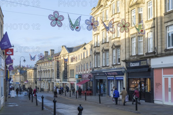 Christmas street decorations hang above quiet shopping street in January, town centre of Chippenham, Wiltshire, England, UK