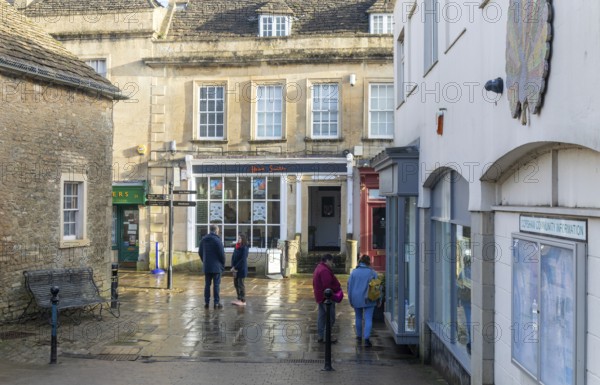 People in street wet surfaces after rain in town centre of Corsham Wiltshire, England, UK
