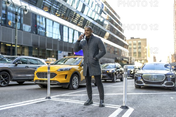 Man standing on a new york city street, making a phone call while surrounded by urban traffic and modern buildings, representing communication and a dynamic lifestyle