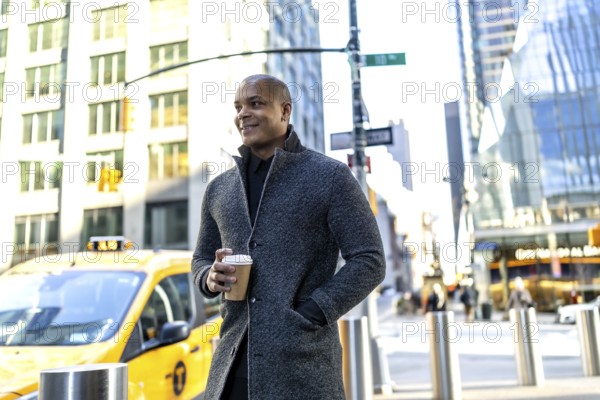 Confident black professional in smart casual coat holding a takeaway coffee cup, walking a busy manhattan street with yellow taxi and modern buildings, embodying urban workday energy