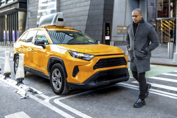 Well dressed man, embodying urban professionalism and sophisticated style, walking purposefully past a modern yellow taxi cab on a busy city street in manhattan