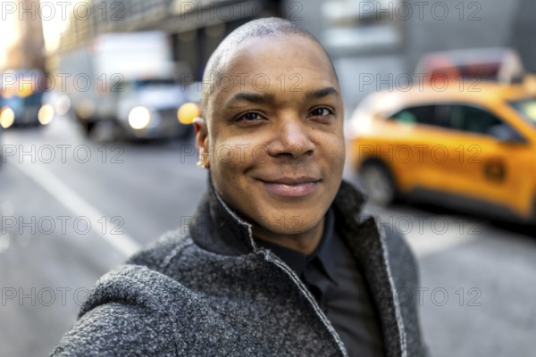 Happy african american businessman standing on a busy new york city street with blurred taxis and traffic, reflecting urban professional life and success