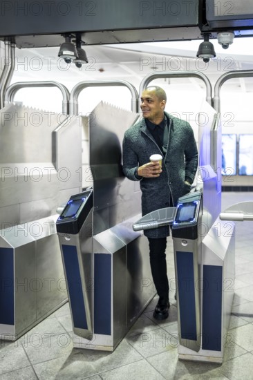 Professional man entering a modern subway station, confidently navigating the turnstile system while holding a coffee cup, representing urban transit and daily commuting in manhattan