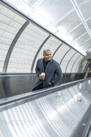Professional businessman riding a subway escalator in manhattan, holding coffee and smiling as he commutes, capturing urban energy, morning routine and confident, stylish city life