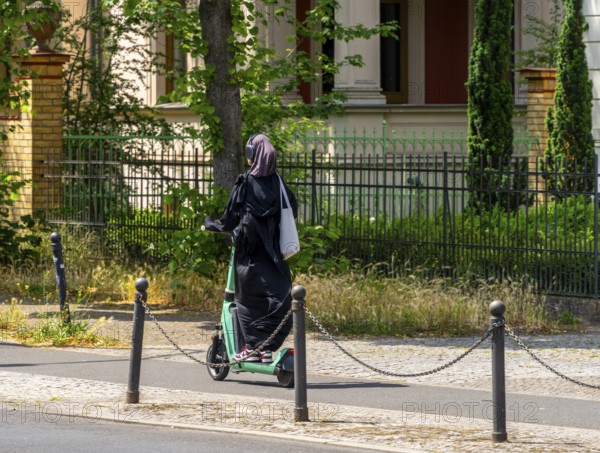 Woman wearing headphones riding on an electric scooter, Potsdam, Brandenburg, Germany