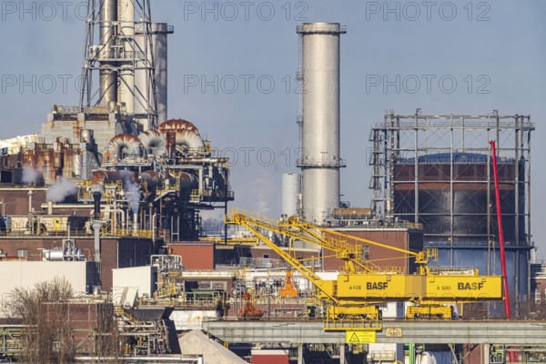 BASF factory site with chemical plants and chimneys. Baden aniline and soda factories. chemical plant. Port cranes unloading a cargo ship. Ludwigshafen am Rhein, Rhineland-Palatinate, Germany