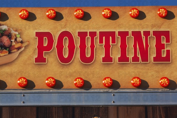 Close-up of the word Poutine spelled out in bold red letters on tan colored banner, Quebec, Canada