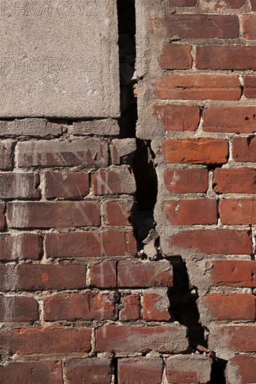 Close-up of large and deep wide open crack on exterior wall of red brick building, Quebec, Canada