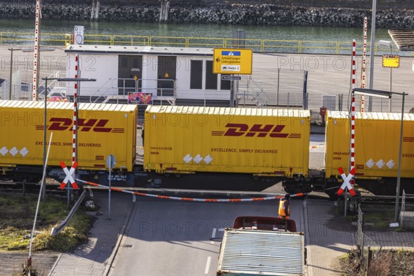 Freight train loaded with yellow container from DHL. Railway crossing in the port area of Mannheim, Baden-Württemberg, Germany